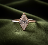 Kite-shaped diamond ring on dark olive green velvet