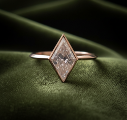 Kite-shaped diamond ring on dark olive green velvet